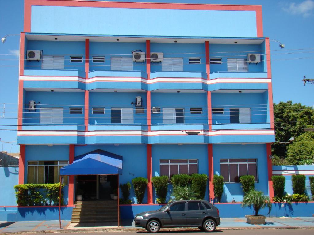 un edificio blu con un'auto parcheggiata di fronte di FRONTIER PALACE HOTEL a Ponta Porã