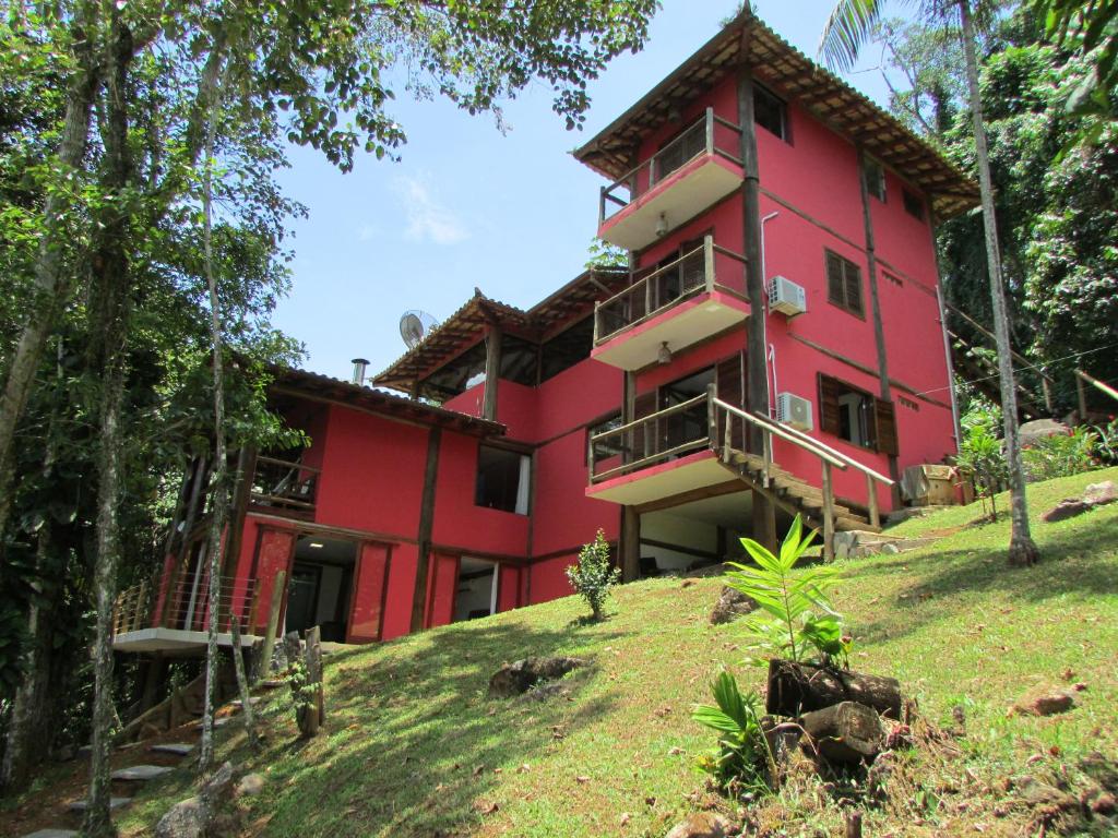a red building on top of a hill with trees at Chalé e Suite Manacá in Ubatuba