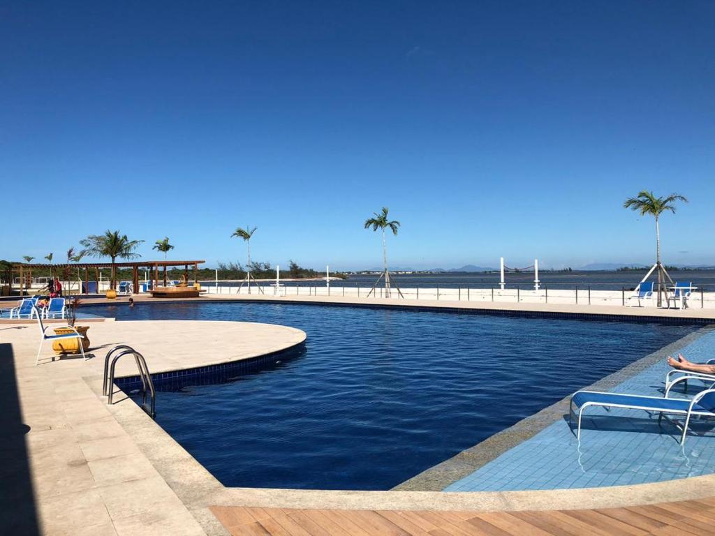 uma piscina ao lado de uma praia com palmeiras em Golden Lake Lazer Completo 2 Qts em Arraial do Cabo