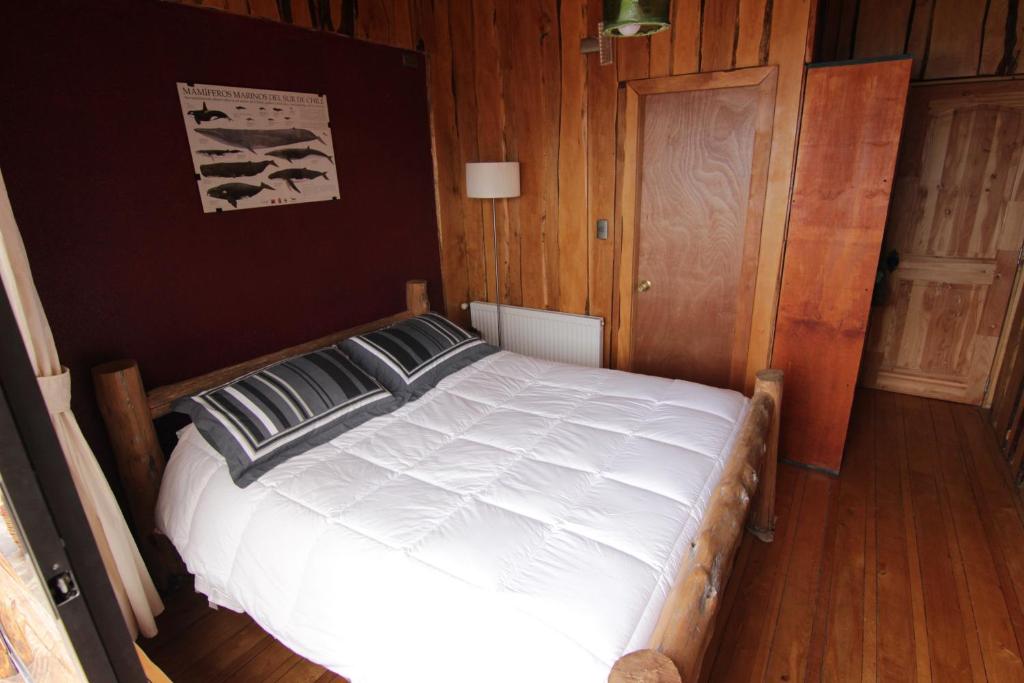 a bedroom with a white bed with wooden walls at Hotel Mitos in Quellón