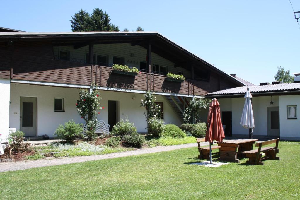 a house with a table and an umbrella in the yard at Ferienwohnungen Benedikt in Villach
