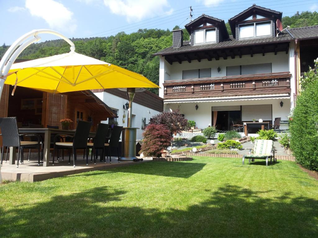 un cortile con un ombrello giallo e una casa di Ferienwohnung am Sulzbach a EuÃŸerthal