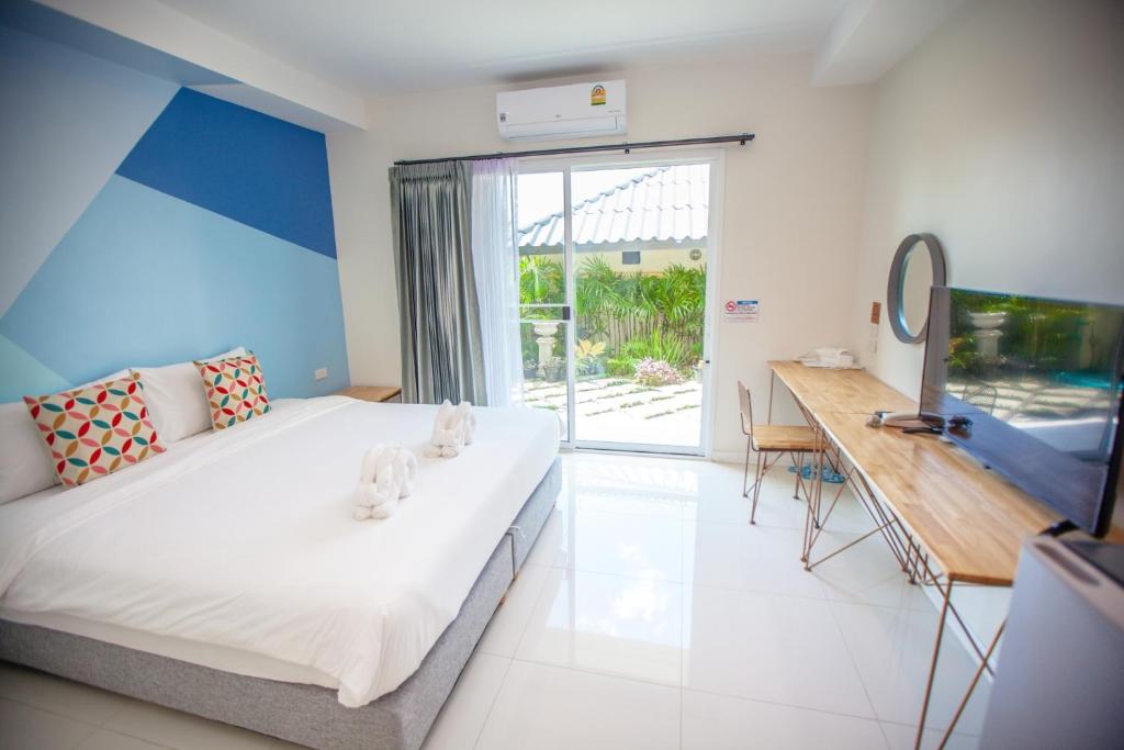 Dormitorio con cama, escritorio y TV en iRabbit Hotel, en Prachin Buri