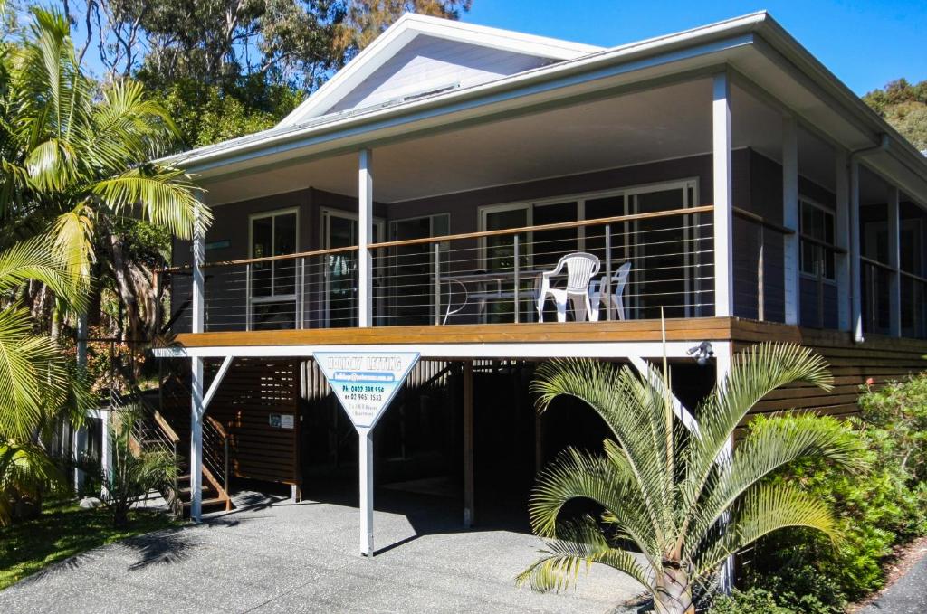 a house with a balcony with a chair on it at Blue Vogue Apt at Blueys Beach in Blueys Beach