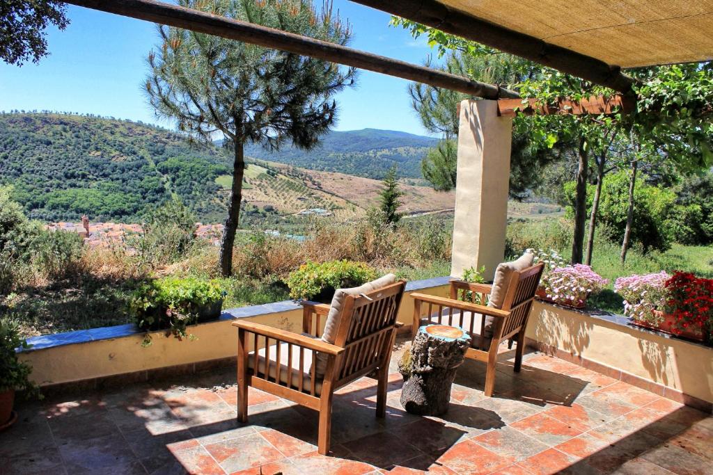 two wooden chairs sitting on a patio with a view at Cielo Abierto in Berzocana