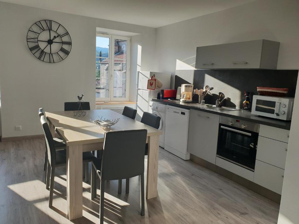 una cocina con mesa y sillas y un reloj en la pared en APPARTEMENT ROUGE, en Saint-Anthème