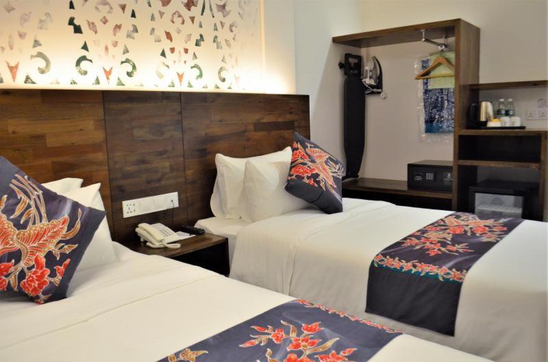 a hotel room with two beds and a phone at Serapi Hotel in Kuching