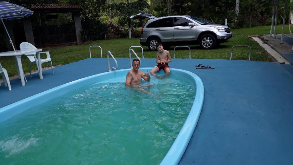 two young boys are sitting in a swimming pool at Chácara Sonho Meu in Arujá