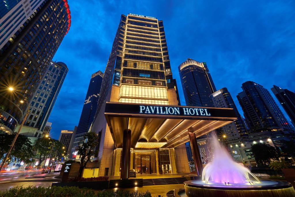 a hotel with a fountain in front of a city at Pavilion Hotel Kuala Lumpur Managed by Banyan Tree in Kuala Lumpur