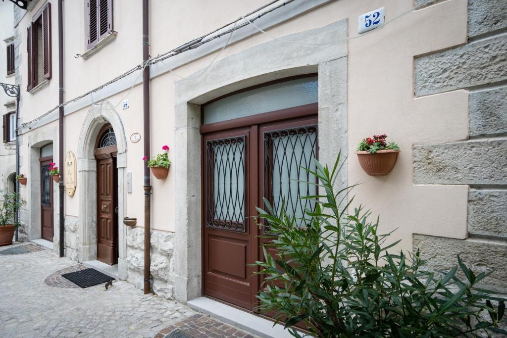 Borgo San Pietro في أغنون: باب بني على مبنى يحتوي على نباتات الفخار