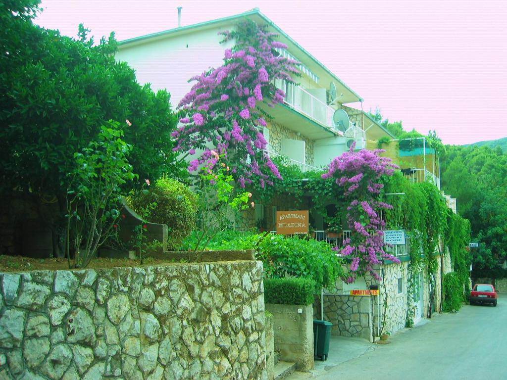 un edificio con flores púrpuras y una pared de piedra en Villa Volga, en Jelsa