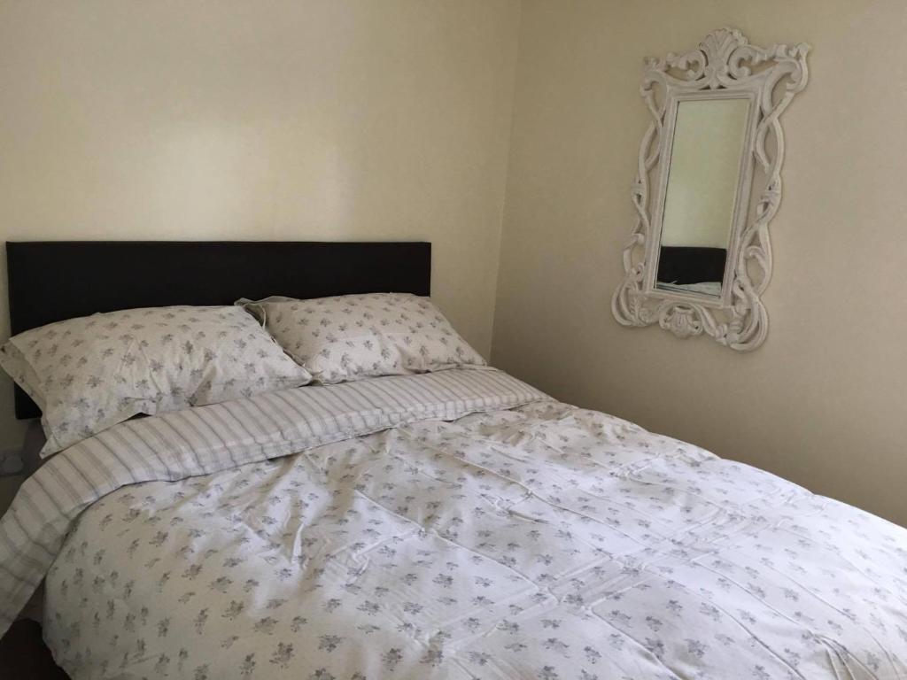 a bed with a white comforter and a mirror at Westmoreland Cottage in Weaverthorpe