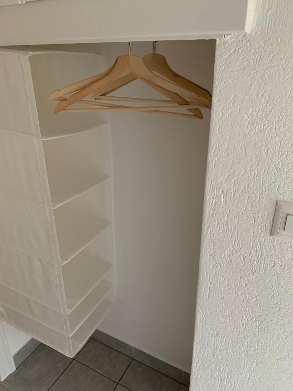 a closet with white shelves and a wooden hanger at Eh!Toi Self Motel in Etoy