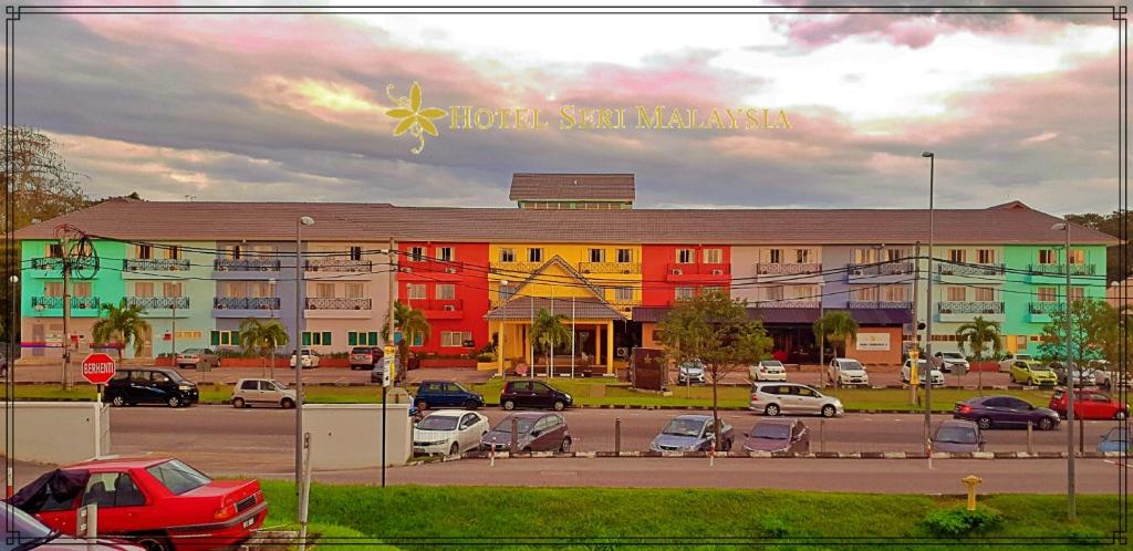 Hotel Seri Malaysia Sungai Petani في سونغاي بيتاني: مبنى كبير به سيارات تقف في موقف للسيارات