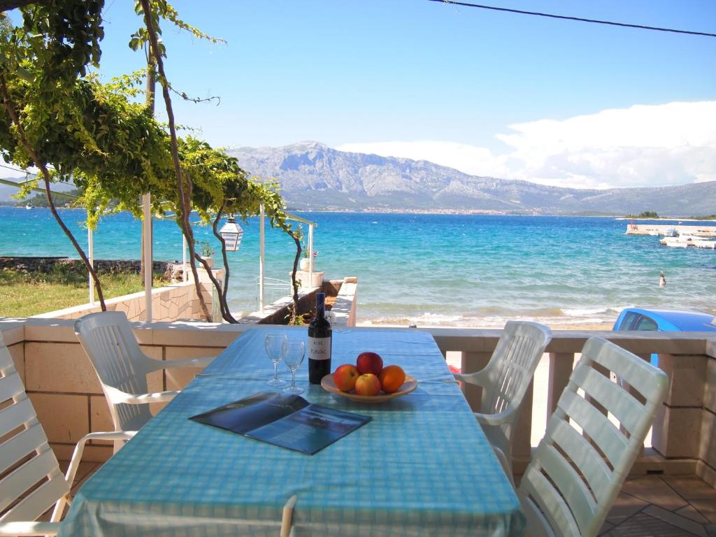 a table with a bottle of wine and a bowl of fruit at Apartments Lumbarda Beach in Lumbarda