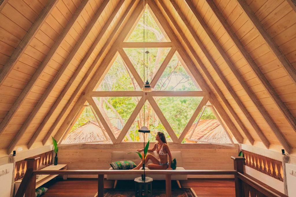 una mujer sentada en un banco en una habitación con una gran ventana en Surf N Sun - Arugam Bay, en Arugam Bay