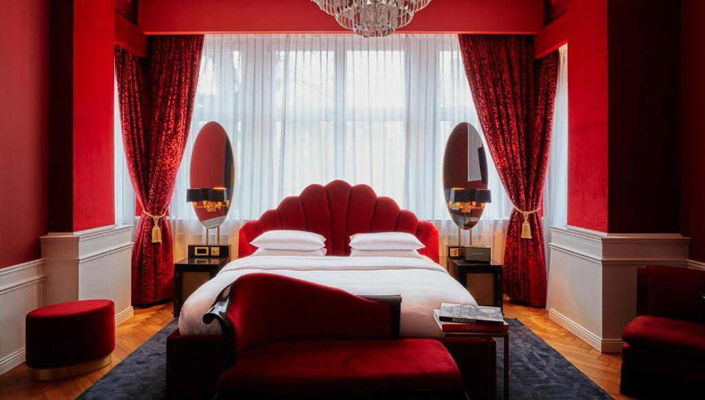 1 dormitorio rojo con 1 cama y 1 silla roja en Provocateur Berlin, a Member of Design Hotels, en Berlín