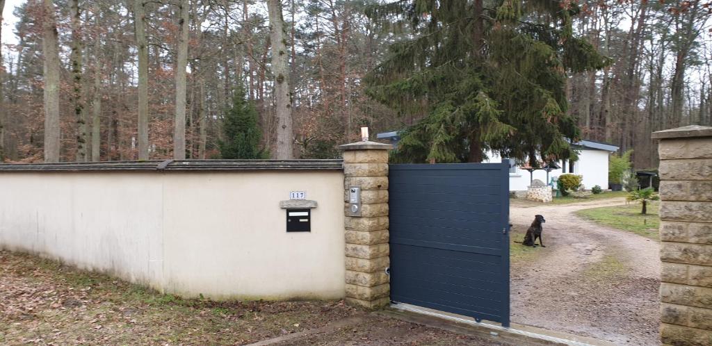 een garage met een blauwe deur naast een muur bij FORET DE FONTAINEBLEAU, chambre entrée privée. in Arbonne