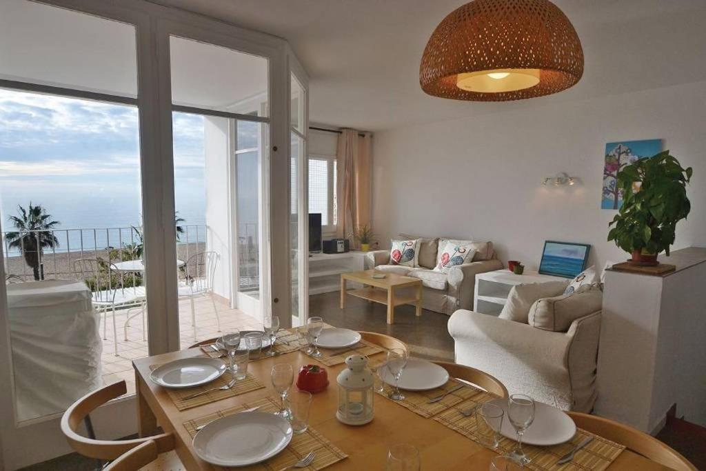 ein Wohnzimmer mit einem Tisch und Meerblick in der Unterkunft Duplex en frente de la playa al lado de Barcelona in Canet de Mar