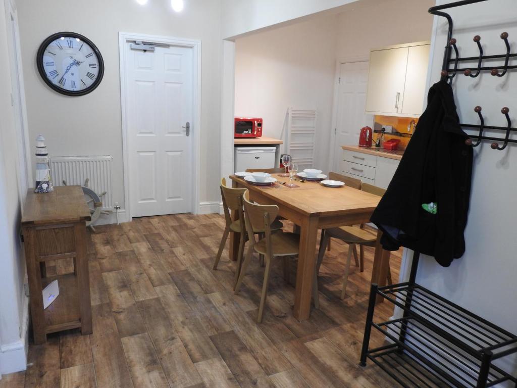 a kitchen with a table and a clock on the wall at Hawen - Barmouth in Barmouth