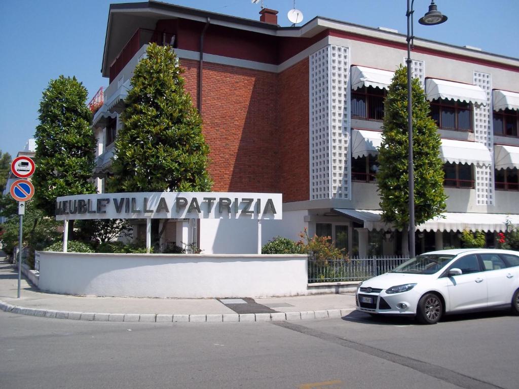 une voiture blanche garée devant un bâtiment dans l'établissement Hotel Meublè Villa Patrizia, à Grado