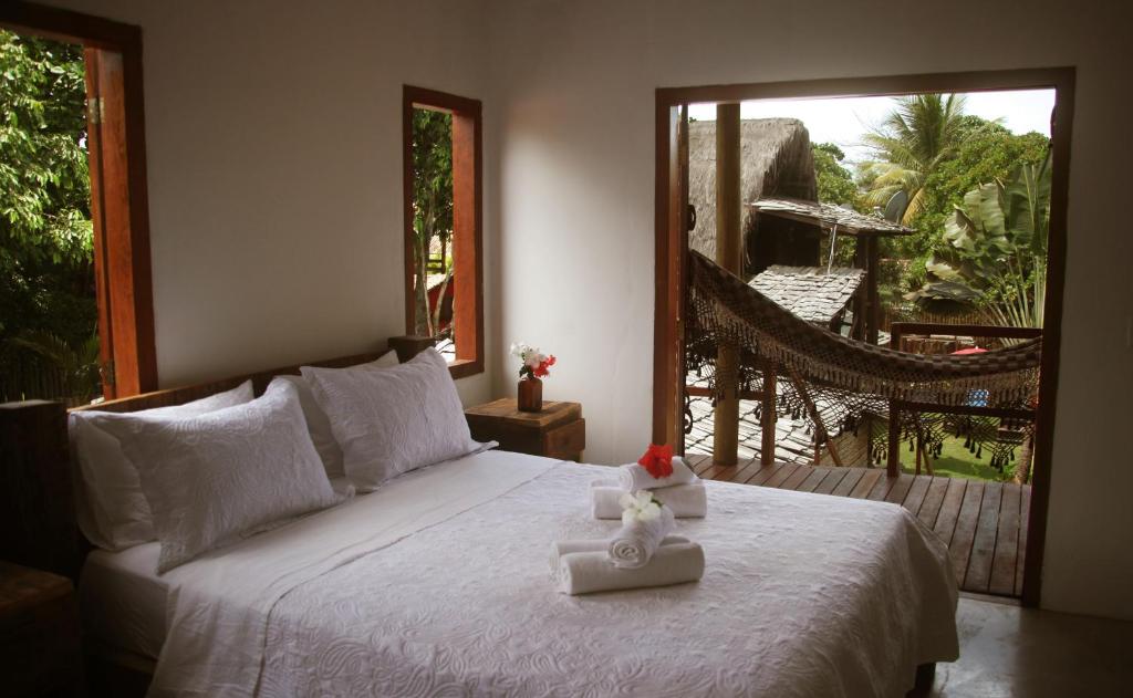 1 dormitorio con 1 cama con sábanas blancas y ventana en Pousada La Villa Caraiva, en Caraíva