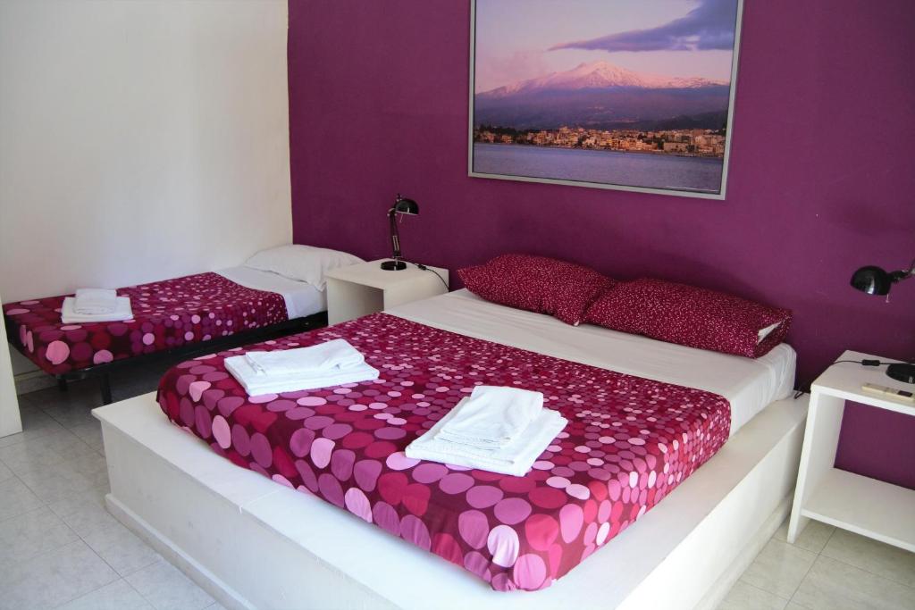 two beds in a room with purple walls at Casa vacanza Civita Catania Centro in Catania