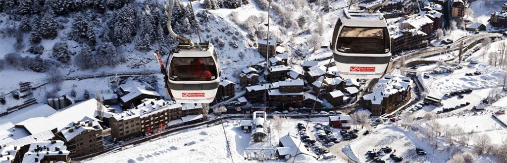 Deux bus sont garés sur une montagne enneigée. dans l'établissement Ski Station Apartments, à Arinsal