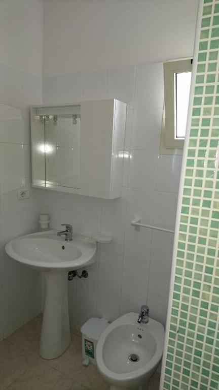 biała łazienka z umywalką i toaletą w obiekcie LA CASA AL MARE a Peschici w mieście Peschici