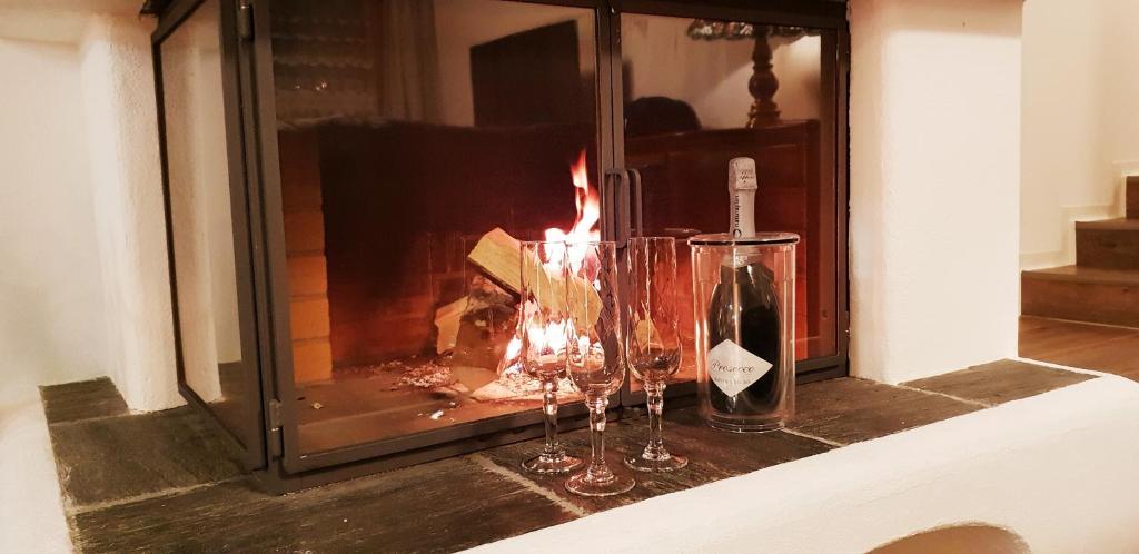 a bottle of wine and two glasses in front of a fireplace at Chasa Melchior in Zernez