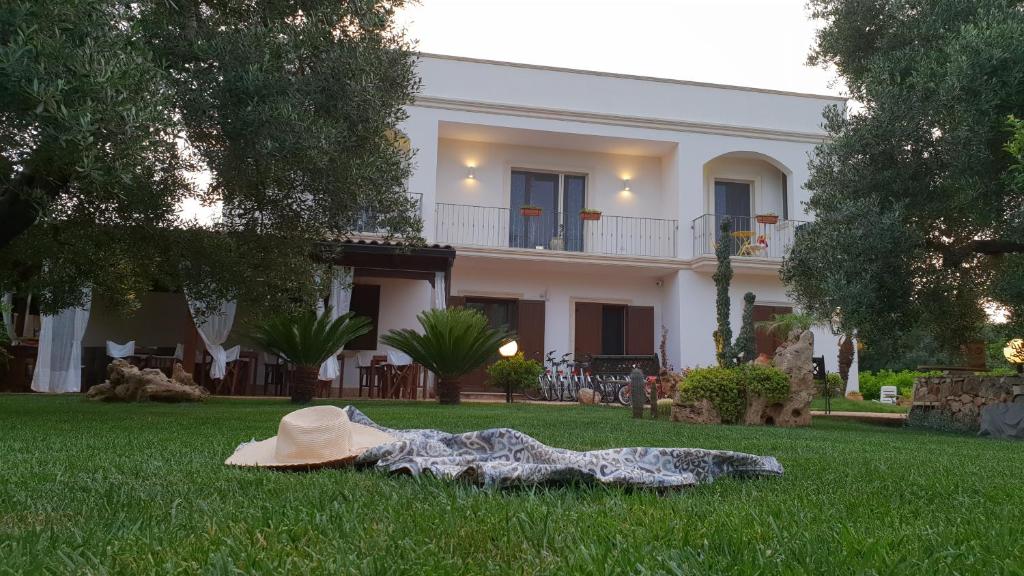 Un cappello seduto sull'erba di fronte a una casa di Villa Sofia Affittacamere a Porto Cesareo