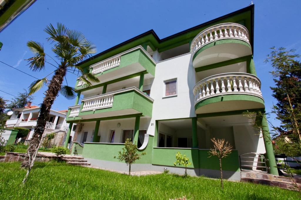 un edificio verde y blanco con una palmera en B88 apartments - Vila Palma, en Sveti Filip i Jakov