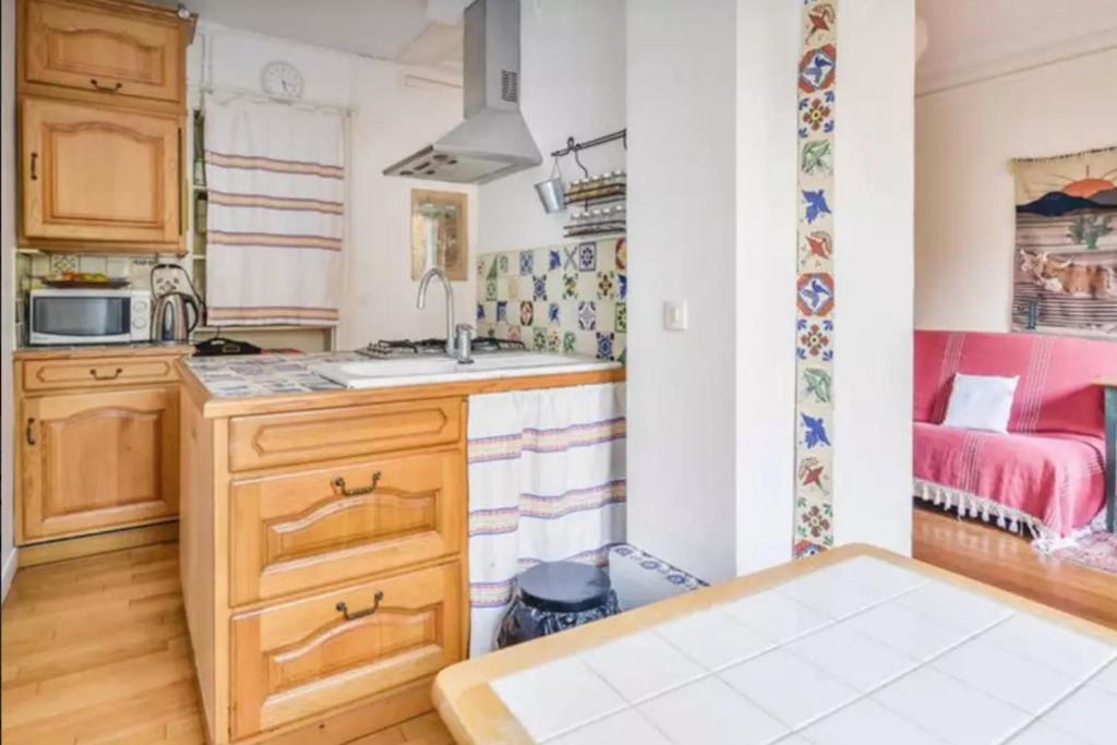une petite cuisine avec un évier et un lit dans l'établissement Appartement de charme de 60 m2 entre Montmartre et Batignolles, à Paris
