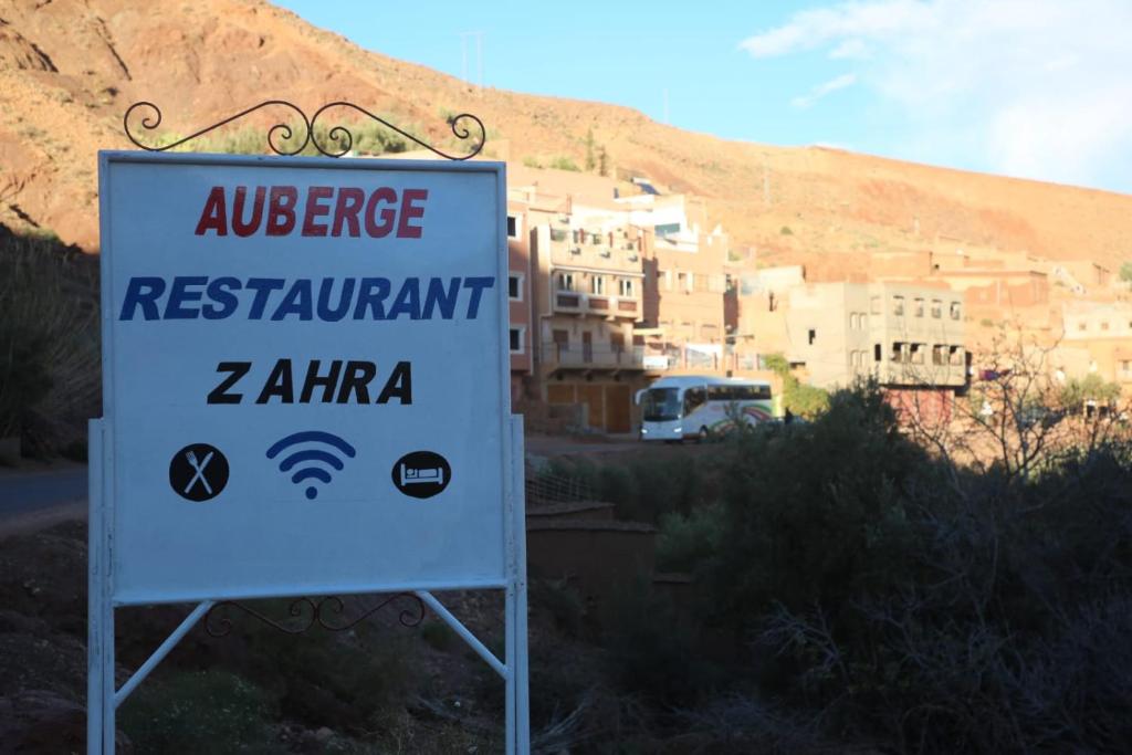 a sign in front of a building with a mountain at Auberge Restaurant Zahra in Boumalne