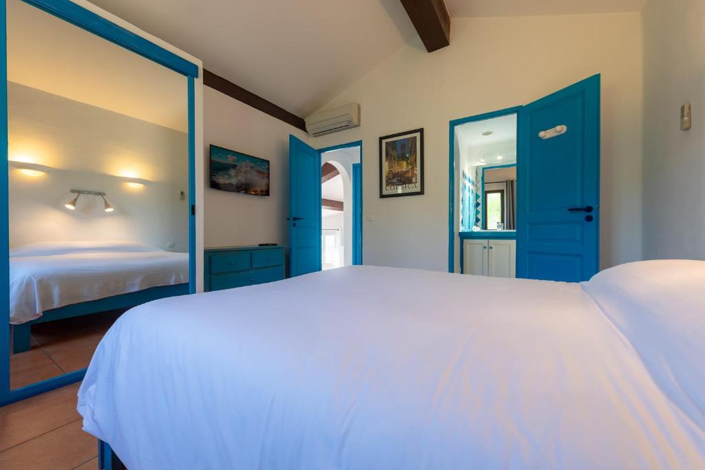 a bedroom with a white bed and blue doors at Résidence Belvedere de Palombaggia in Porto-Vecchio