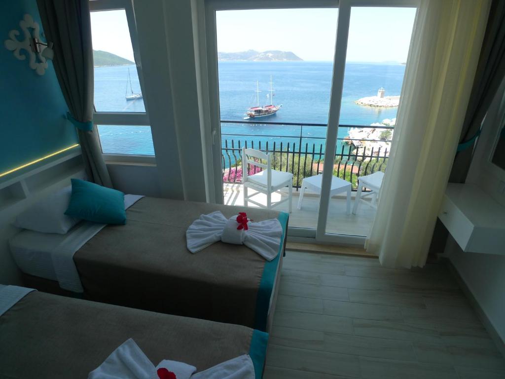 two beds in a room with a view of the ocean at Çakıl Pansiyon in Kaş
