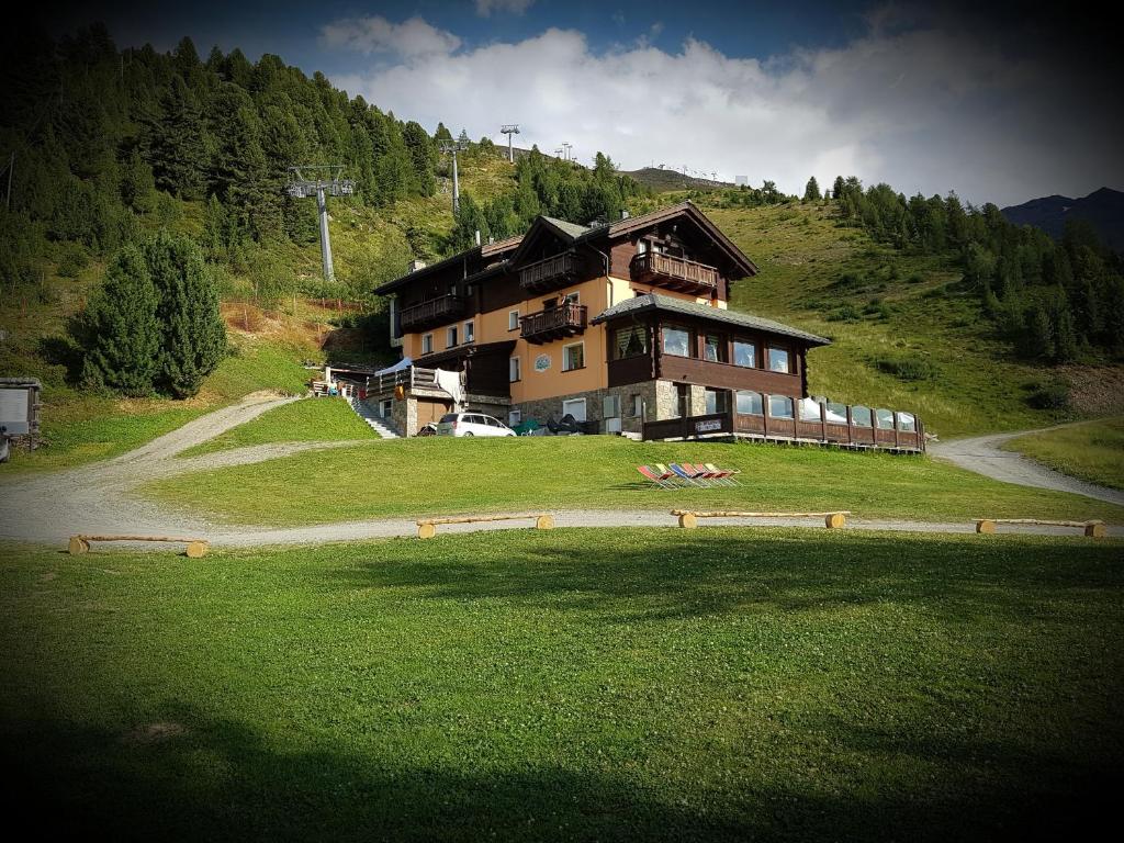 a large house on top of a grassy hill at Chalet Dei Rododendri in Valdisotto