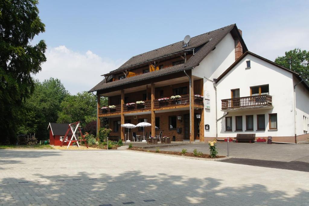 a large white building with a balcony and a playground at Gasthof Schumacher Hotel garni in Freudenberg