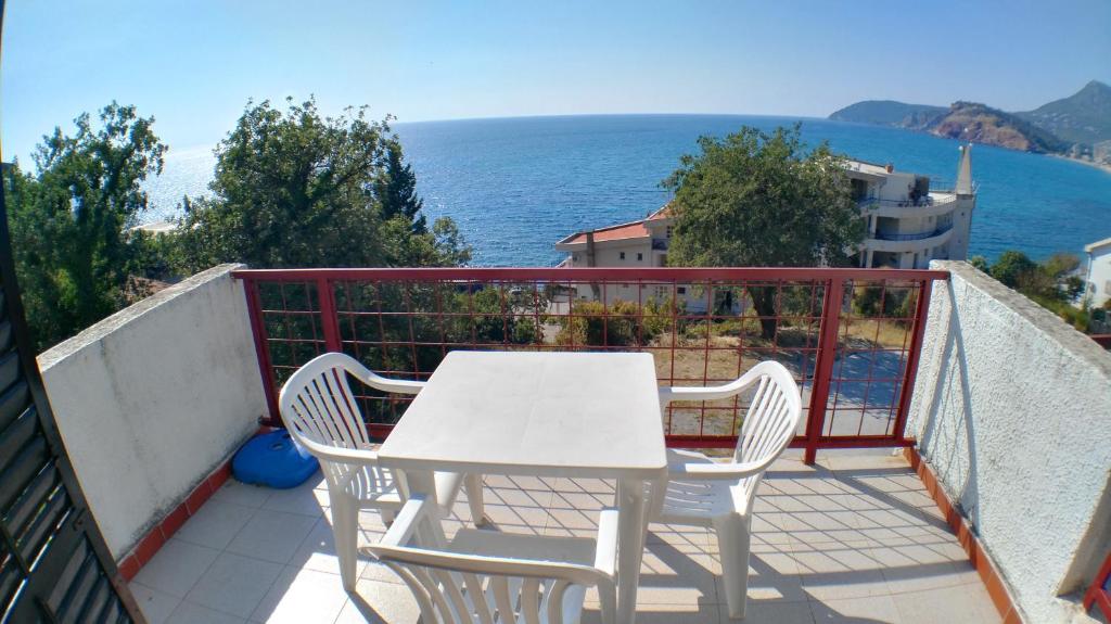 een witte tafel en stoelen op een balkon met uitzicht op de oceaan bij Guesthouse Obala in Sutomore