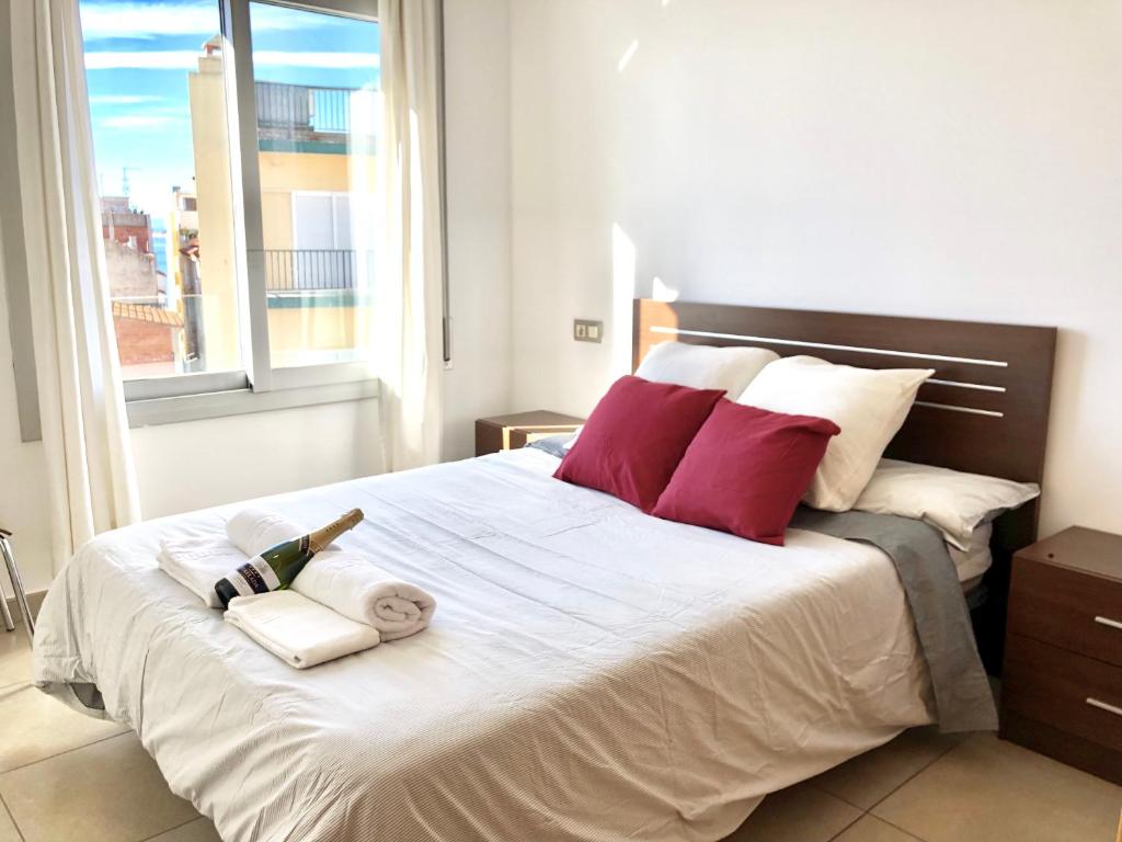 sypialnia z dużym białym łóżkiem z czerwonymi poduszkami w obiekcie Apartament Familiar Av. Tarragona w mieście Roses