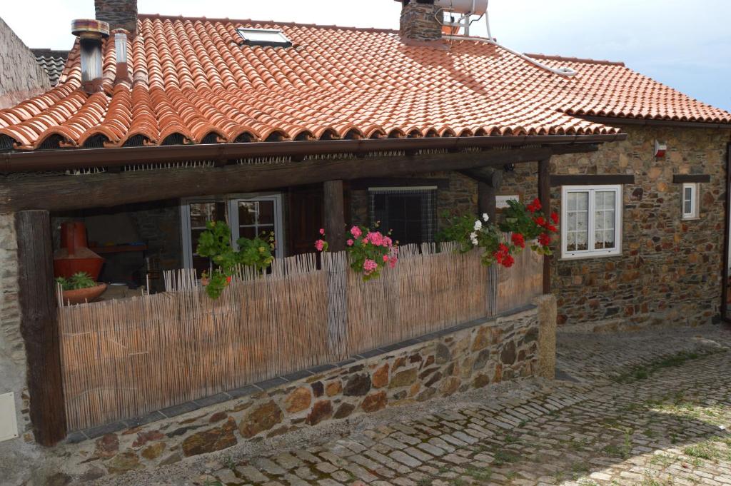 a brick house with a wooden fence and flowers at Apimonte Casa do Pascoal - PN Montesinho in Bragança