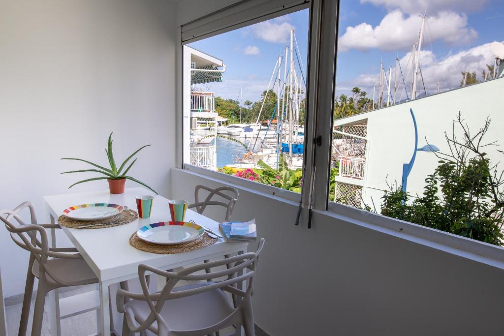 comedor con mesa, sillas y ventana en Beau 3 pièces a la marina des 3 ilets, en Les Trois-Îlets