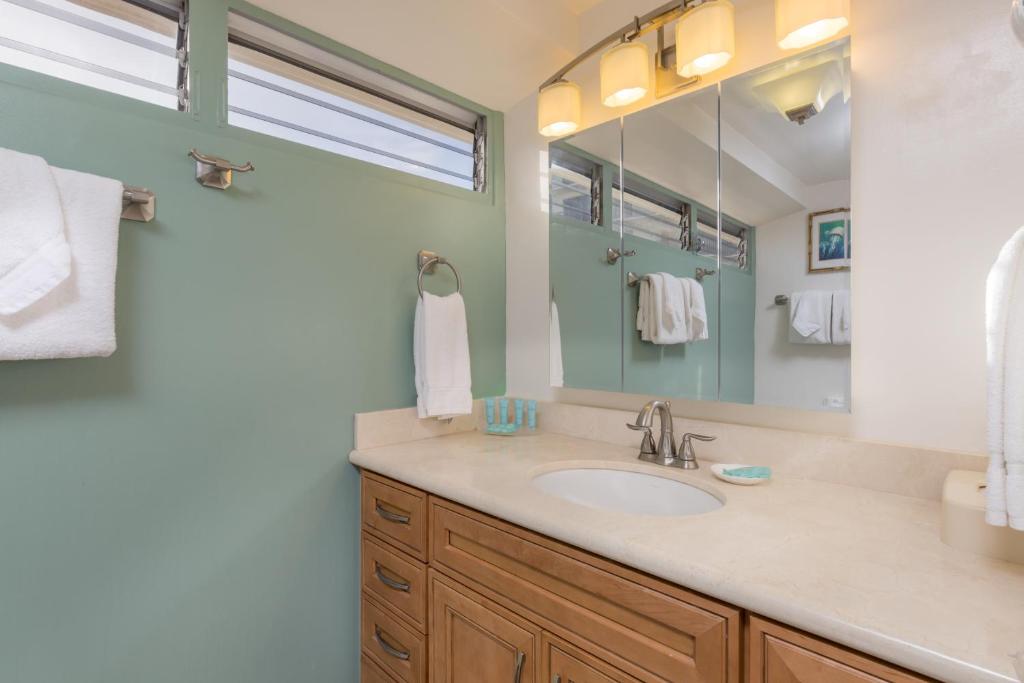a bathroom with a sink and a mirror at Castle Waikīkī Shore in Honolulu