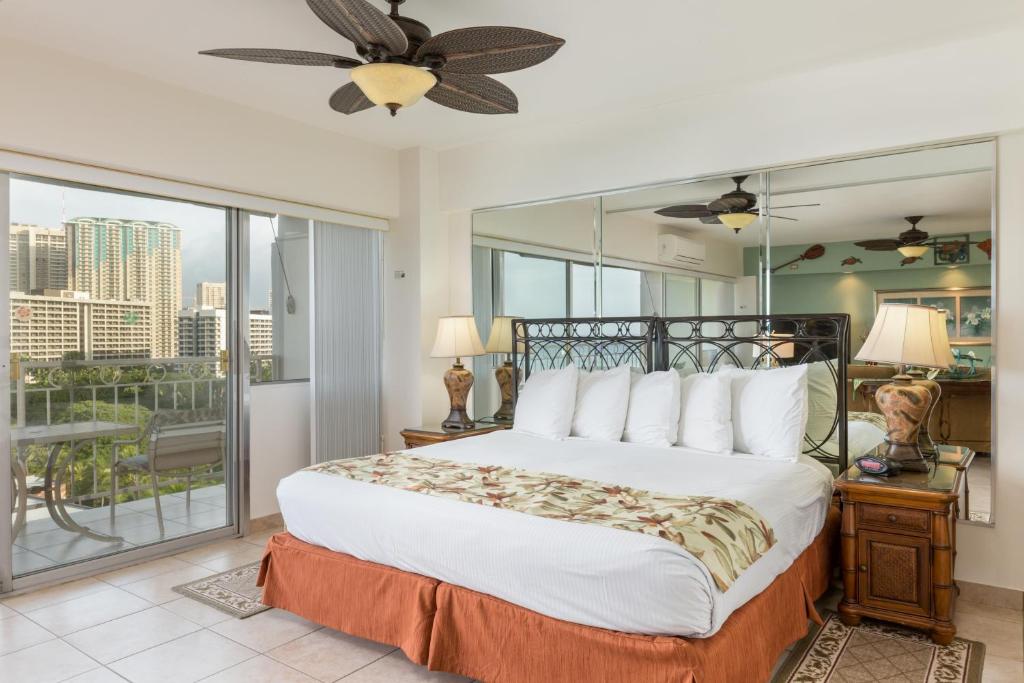 a bedroom with a large bed and a balcony at Castle Waikīkī Shore in Honolulu