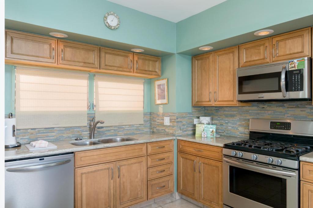 a kitchen with wooden cabinets and a sink and a microwave at Castle Waikīkī Shore in Honolulu