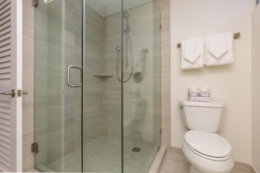 a bathroom with a toilet and a glass shower at Castle Waikīkī Shore in Honolulu