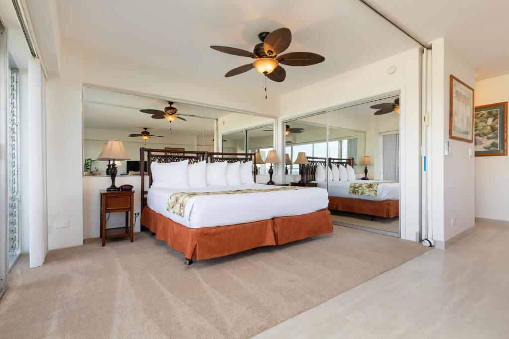 a bedroom with a bed and a large mirror at Castle Waikīkī Shore in Honolulu