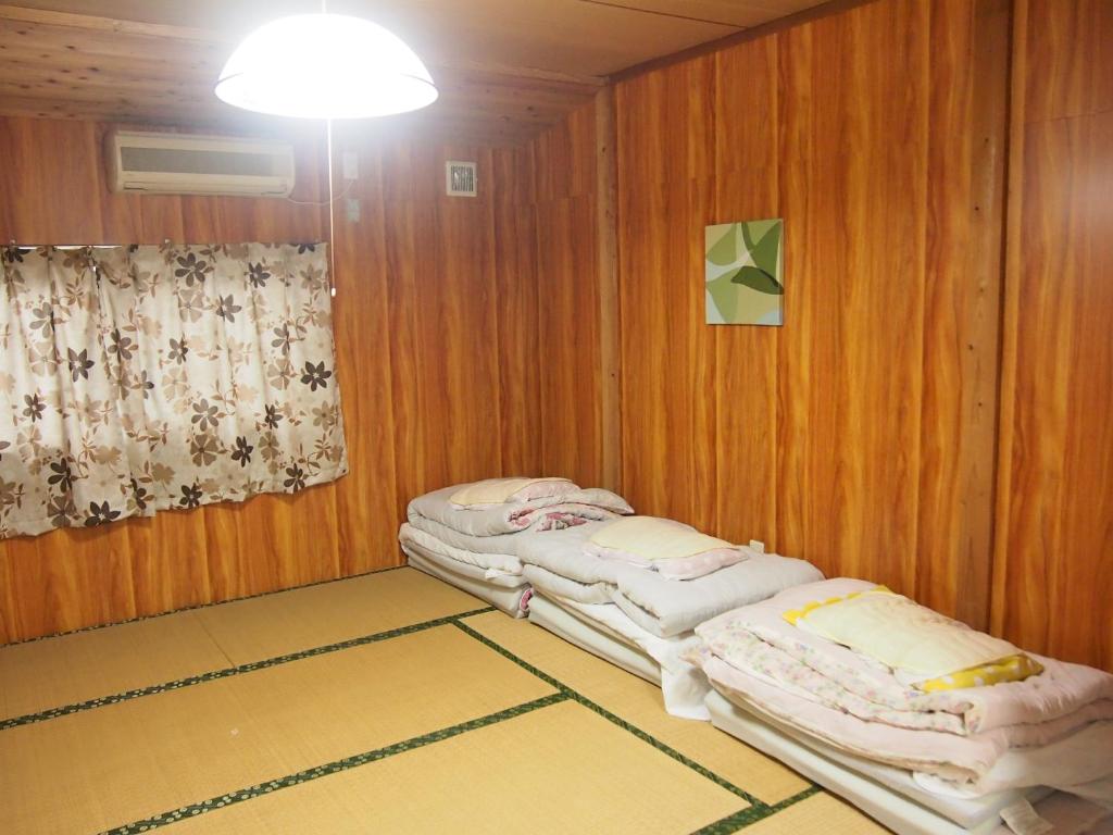 two twin beds in a room with wooden walls at Tirol in Yakushima