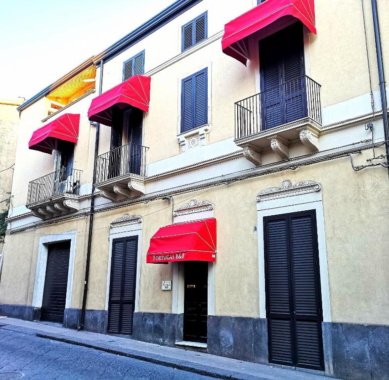 un edificio con sombrillas rojas en una calle en Tortugas B&B, en Giarre