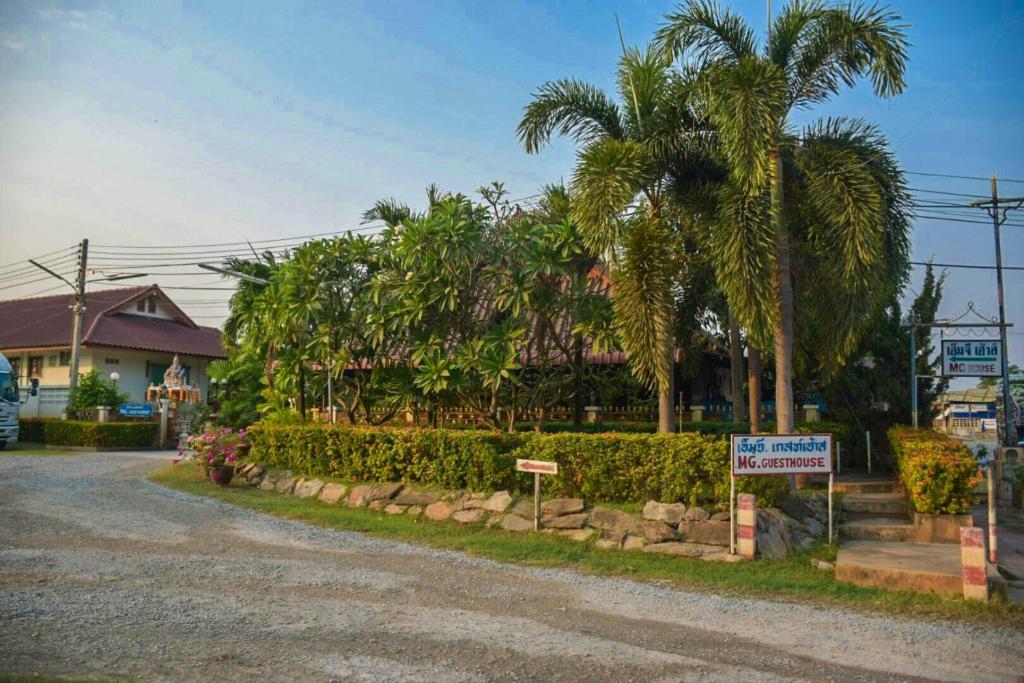 una calle con una palmera al lado de una casa en MG Guesthouse, en Sukhothai